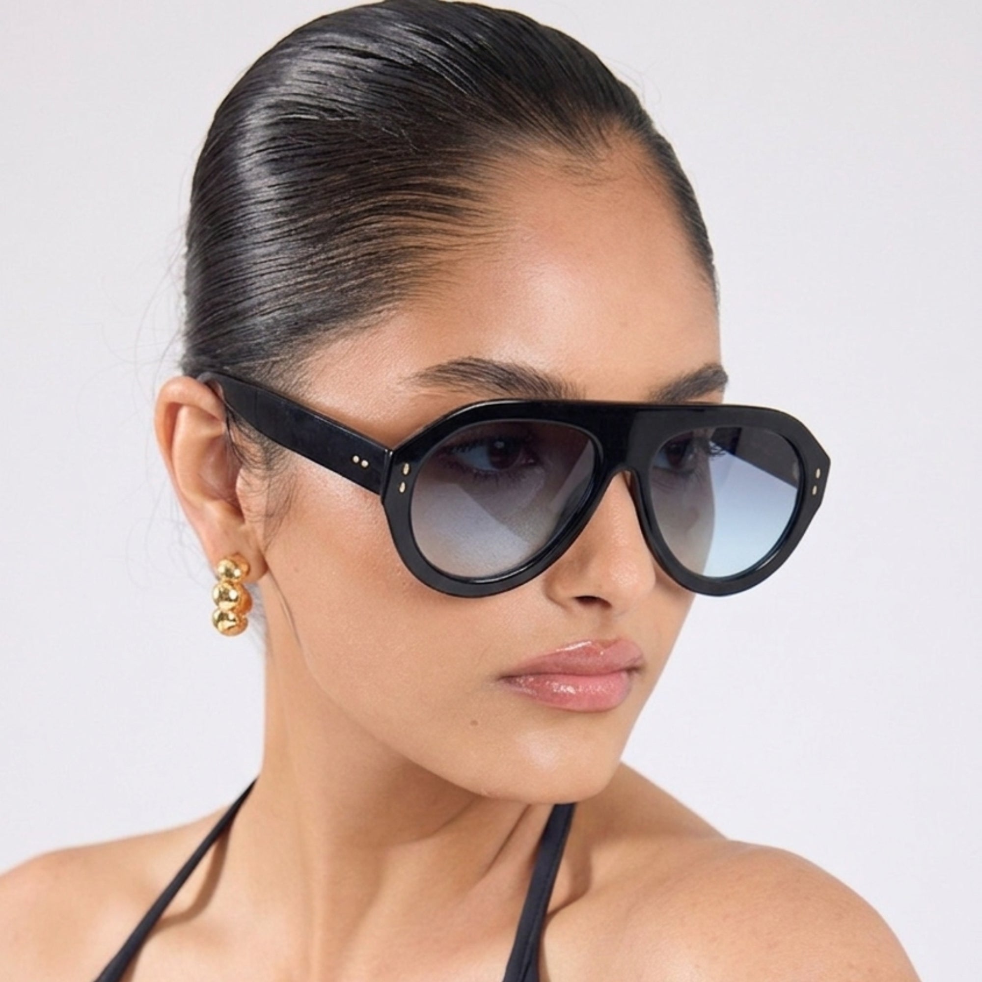 Femme portant les lunettes de soleil Eclipse noires Osour Eyewear avec monture aviateur oversize noire et verres bleus dégradés