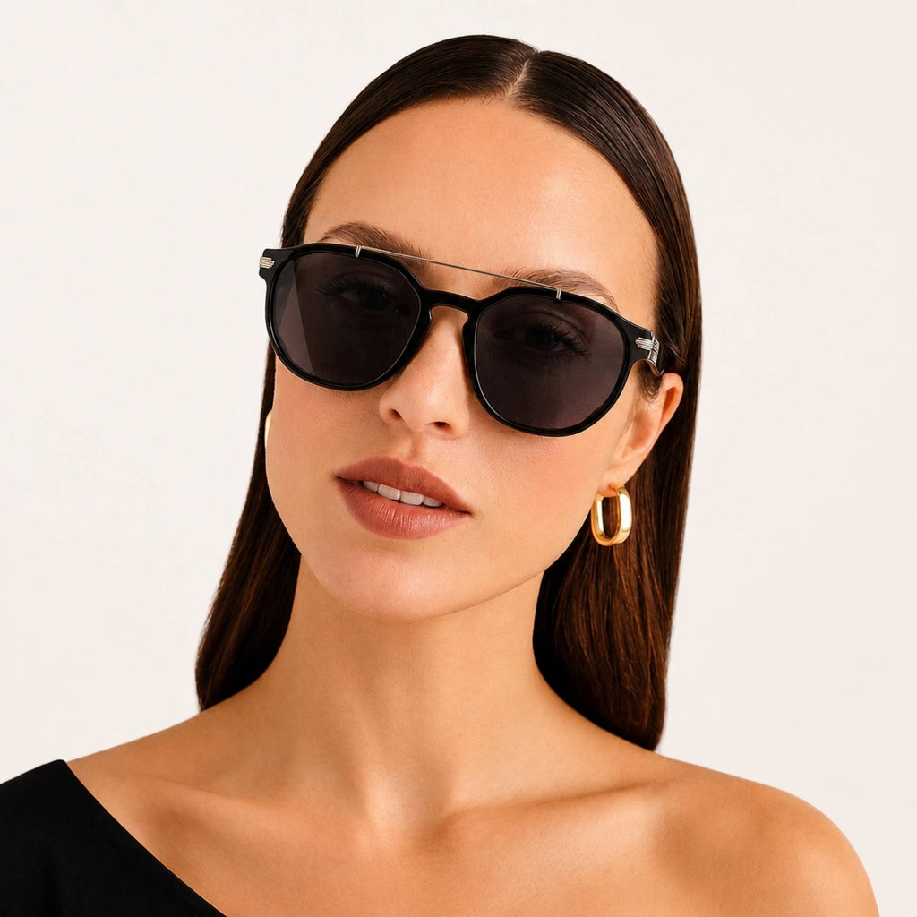 Femme portant les lunettes de soleil La Selva Osour Eyewear avec monture noire, verres noirs et détail métallique sur le pont
