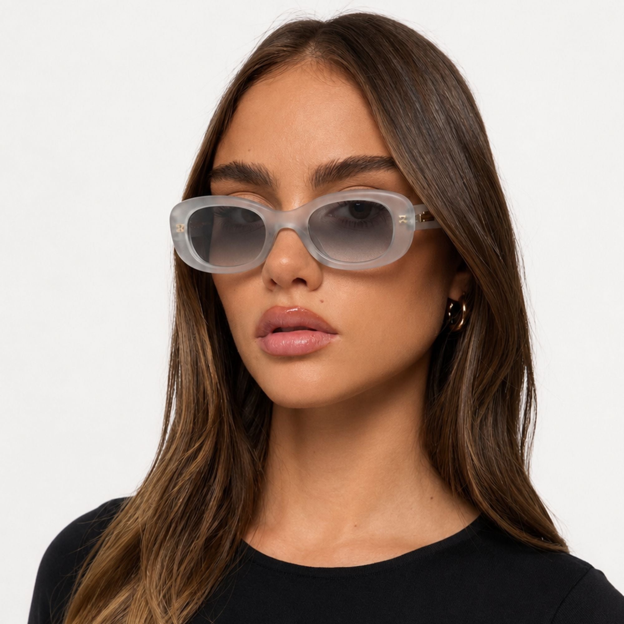 Lunettes de soleil Osour Alba Grey à monture ovale gris translucide avec verres gris dégradés, portée par mannequin femme