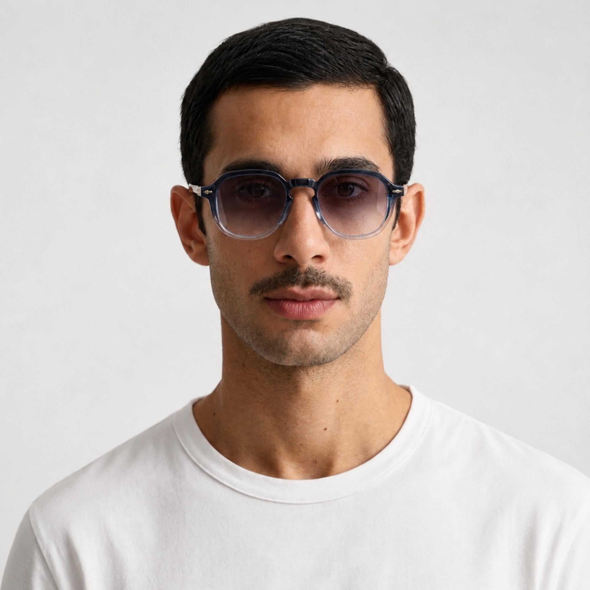 unettes de soleil Lior Osour Eyewear avec monture transparente bleu fumé, branches métalliques dorées et verres dégradés portées oar un mannequin homme